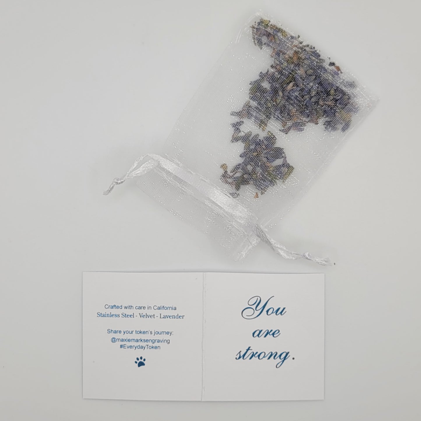 A lavender sachet and printed affirmation card reading “You are strong,” highlighting the handcrafted packaging details and materials included with the I Am Strong affirmation token.